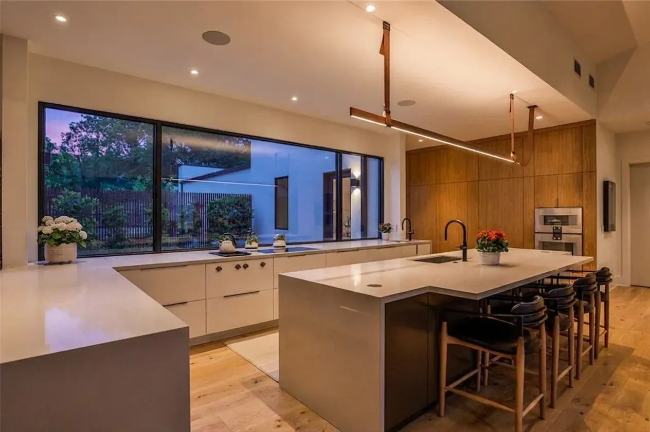 Daniel Allen Designs contemporary kitchen with white cabinetry, quartz island, and wood panel in Buckhead, Georgia
